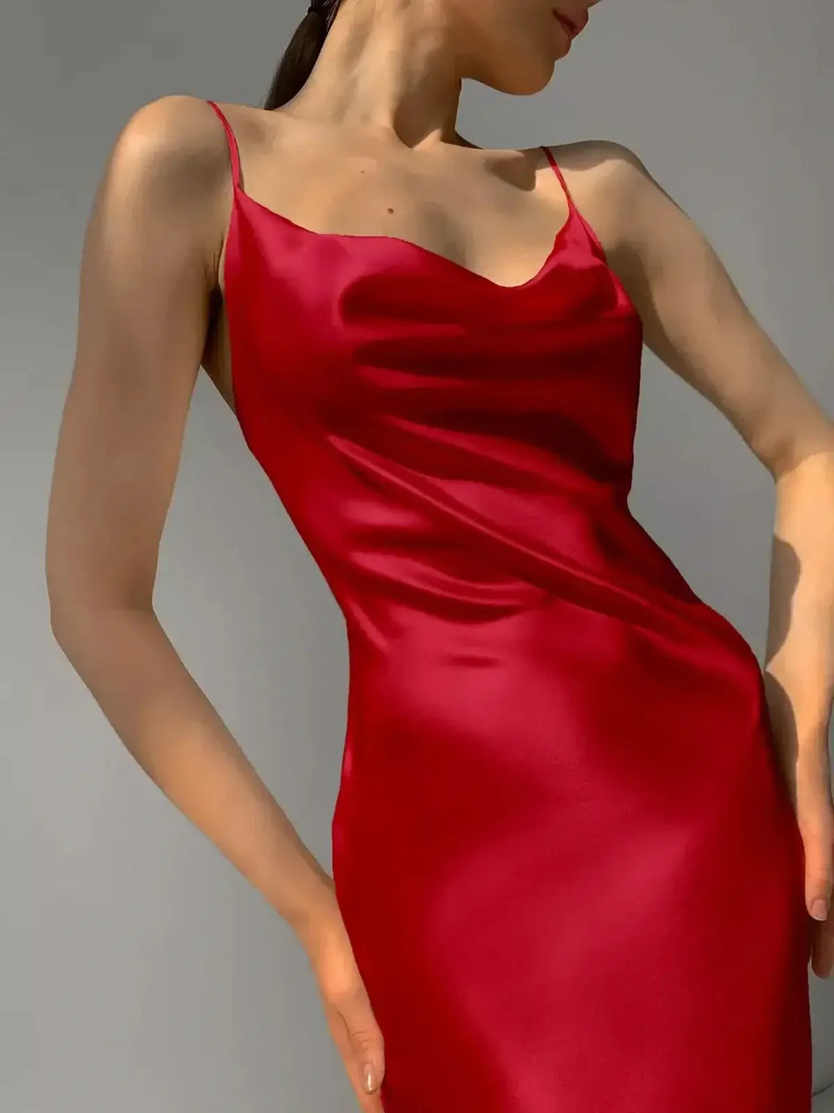 Sleek satin crimson midi dress featuring a seductive silhouette and elegant drape, perfect for formal occasions.