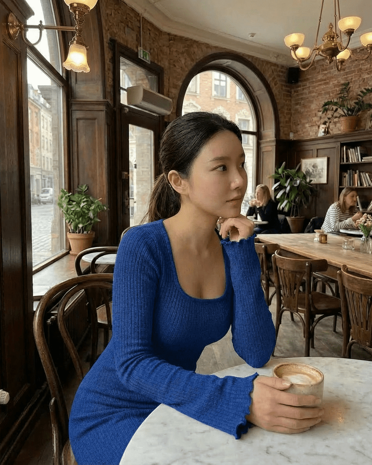 Model wearing the Crimsona Maxi Dress in blue, enjoying coffee at a café, highlighting its elegant design.