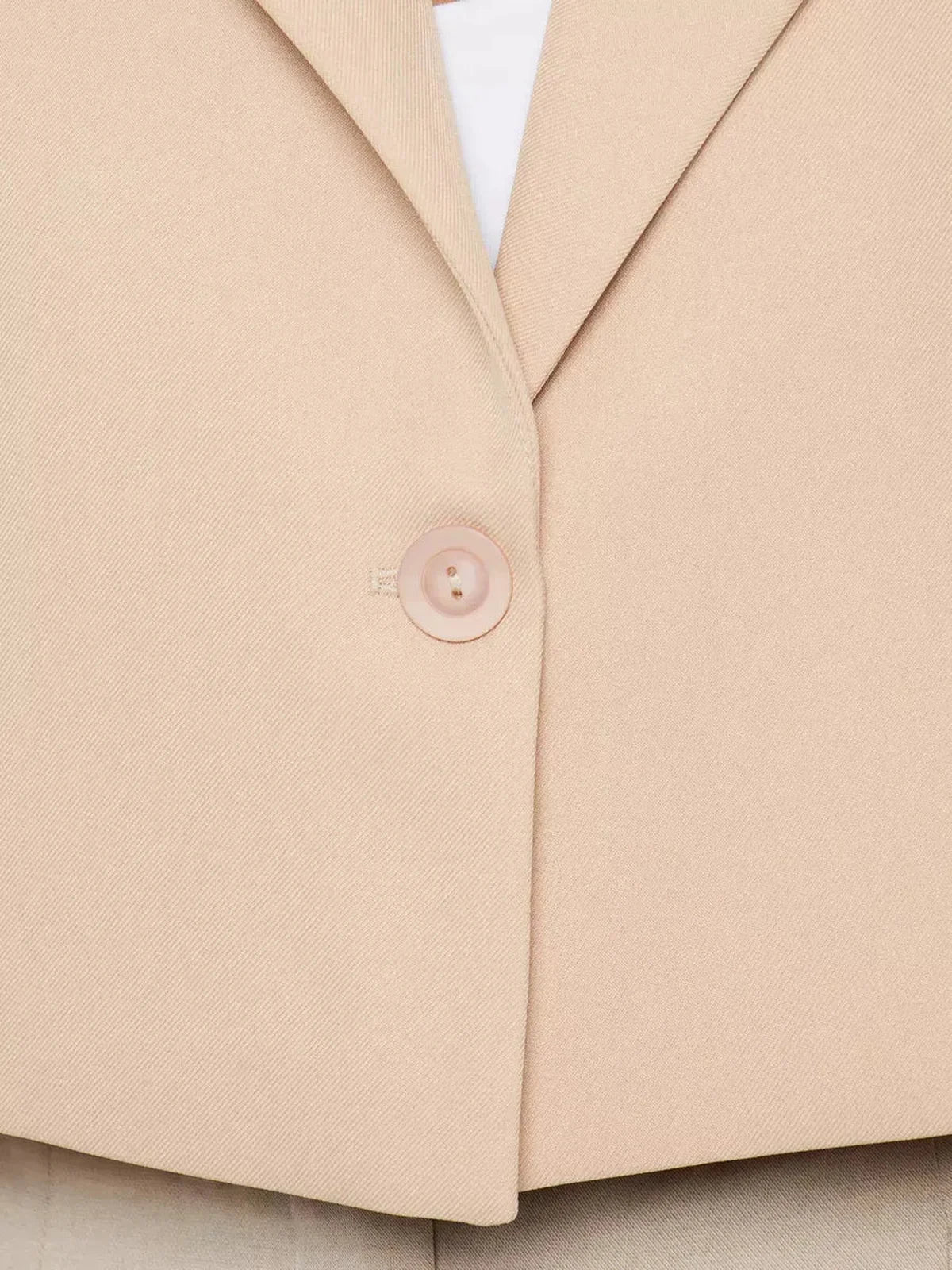Close-up of the Sahara Blazer by Lauven, showcasing the button detail on a beige cropped oversized jacket.