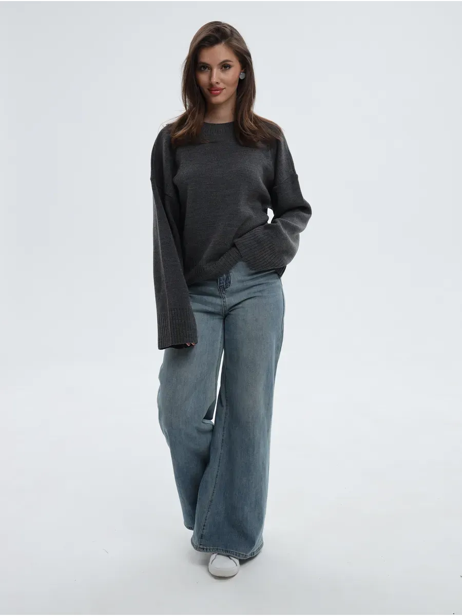Woman wearing Aria Sweater in anthracite gray with wide-leg jeans, showcasing a stylish oversized knit look.