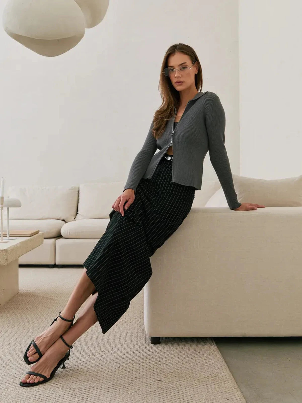 Model wearing Orion Cardigan by Lauven in dark gray, paired with a stylish black striped skirt.
