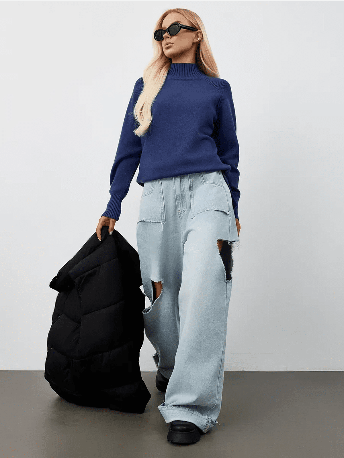 Indigo Sweater by Lauven showcased in an oversized navy blue cashmere knit with high neck, paired with light denim and a puffer jacket.