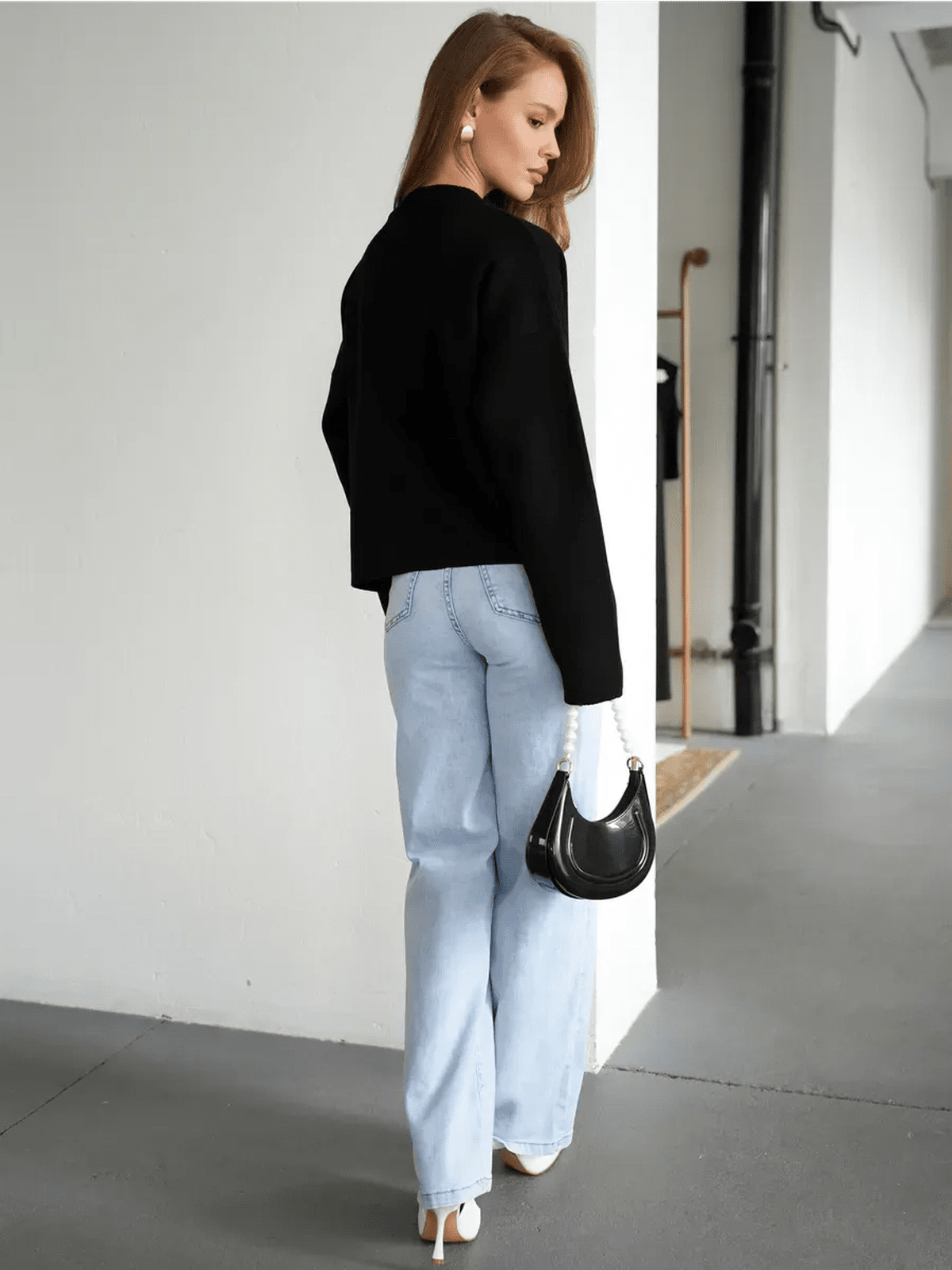 Model wearing the Obsidian Cardigan by Lauven, styled with light blue jeans and a black handbag.