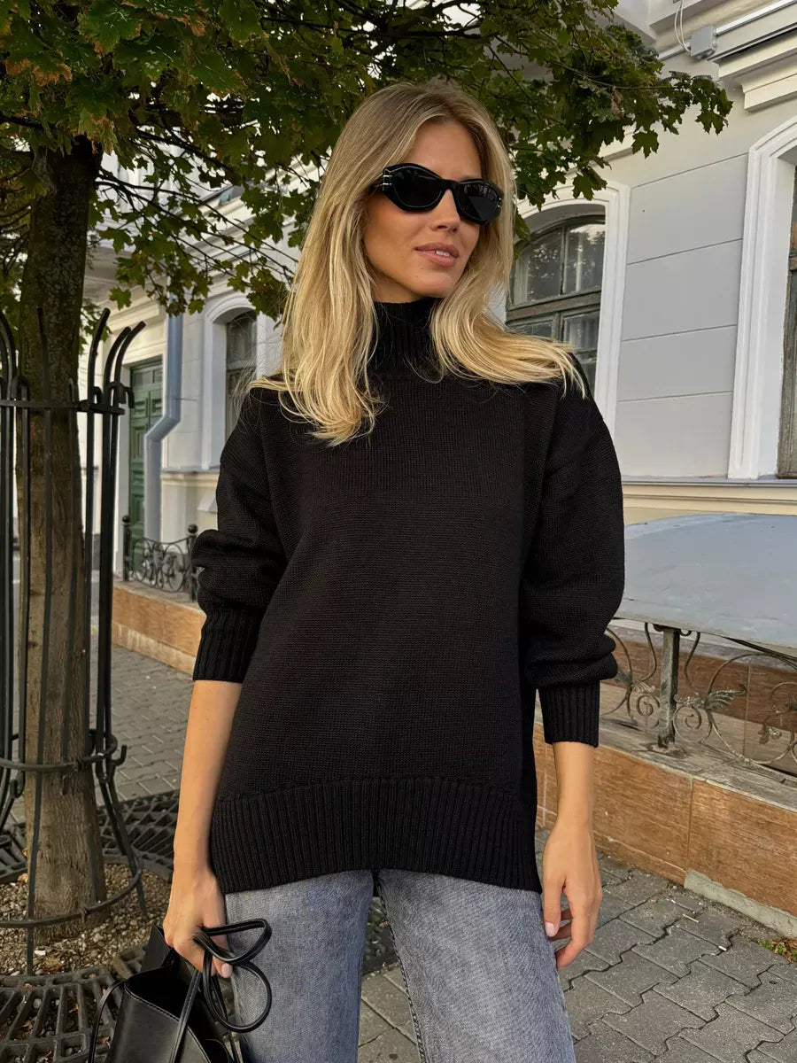 Woman wearing Nyra Sweater, an oversized black wool knit with high turtleneck, stylishly accessorized, by Lauven.