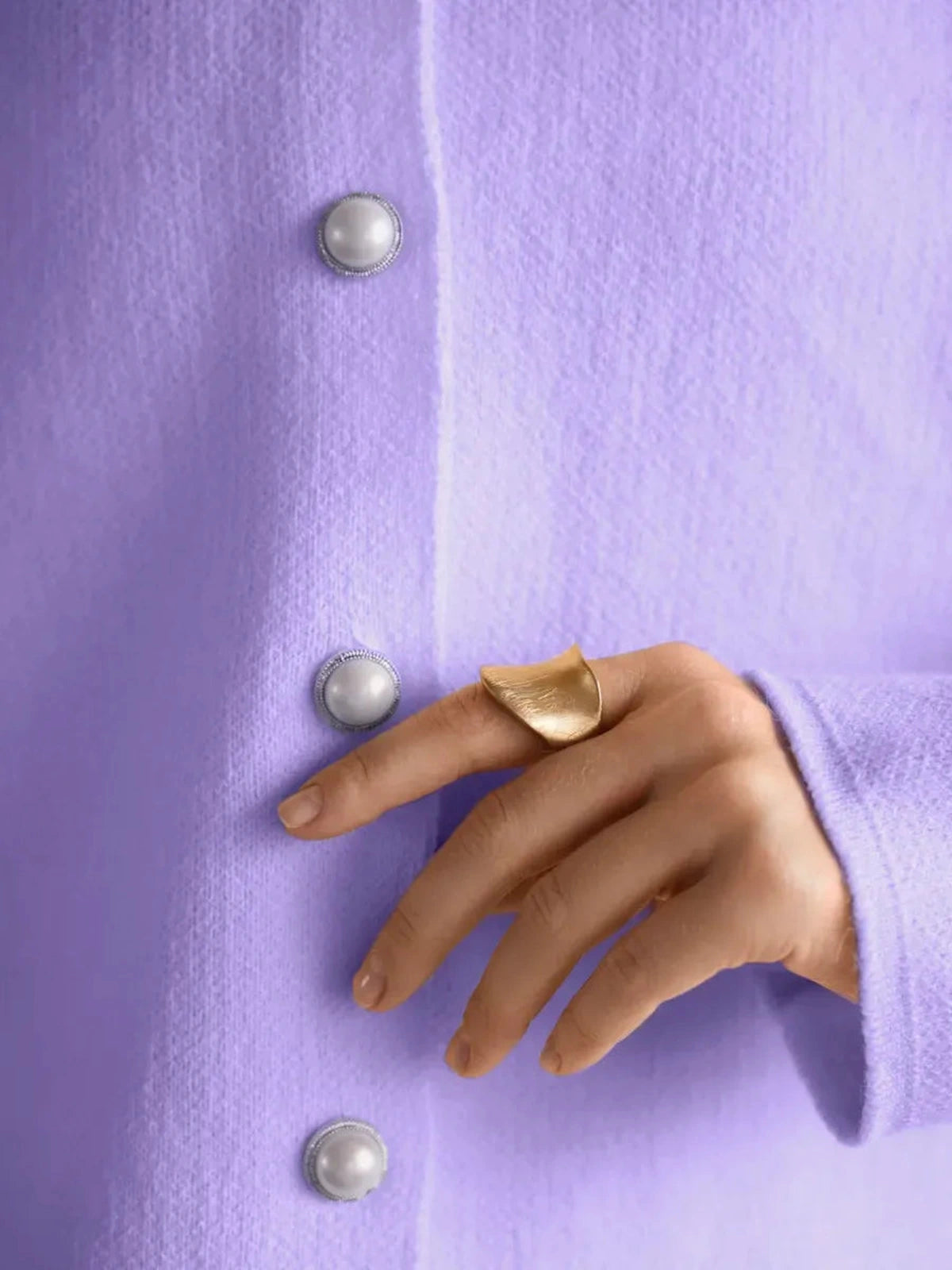 Lavina Cardigan by Lauven in lilac with pearl button closure and stylish hand wearing gold ring.
