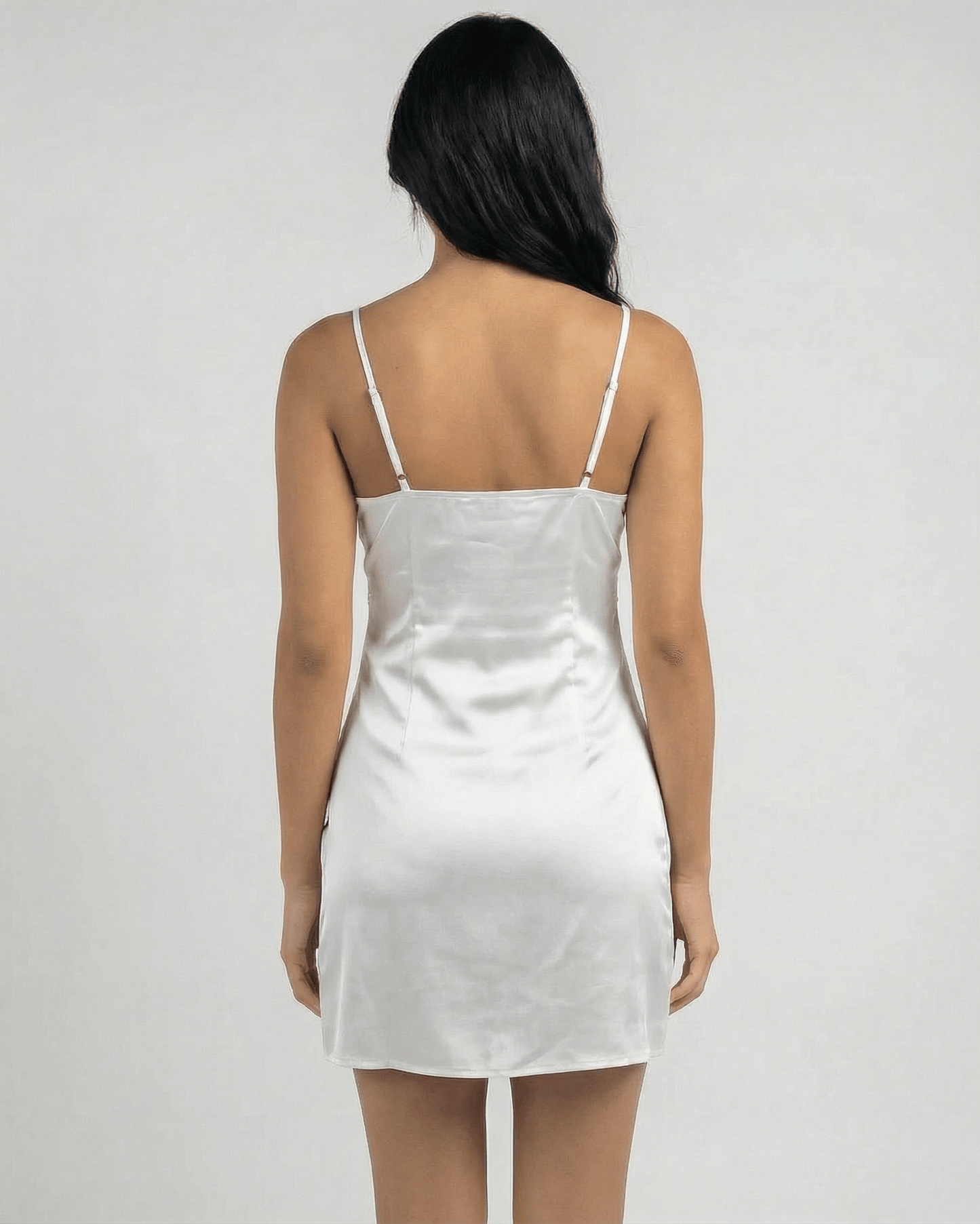 Back view of a woman wearing the Lauven Aurora Mini Dress featuring lace trim and spaghetti straps.