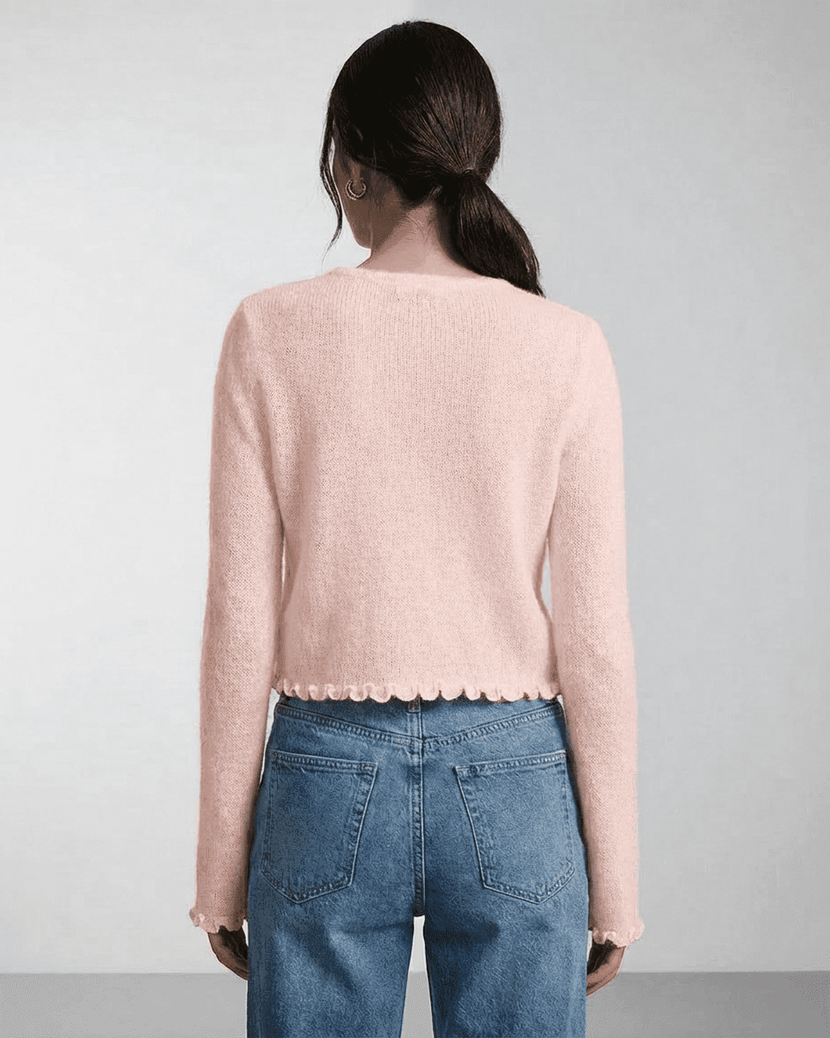 Back view of a woman wearing the Lauven Blush Cardigan with scalloped hem and soft knit texture.