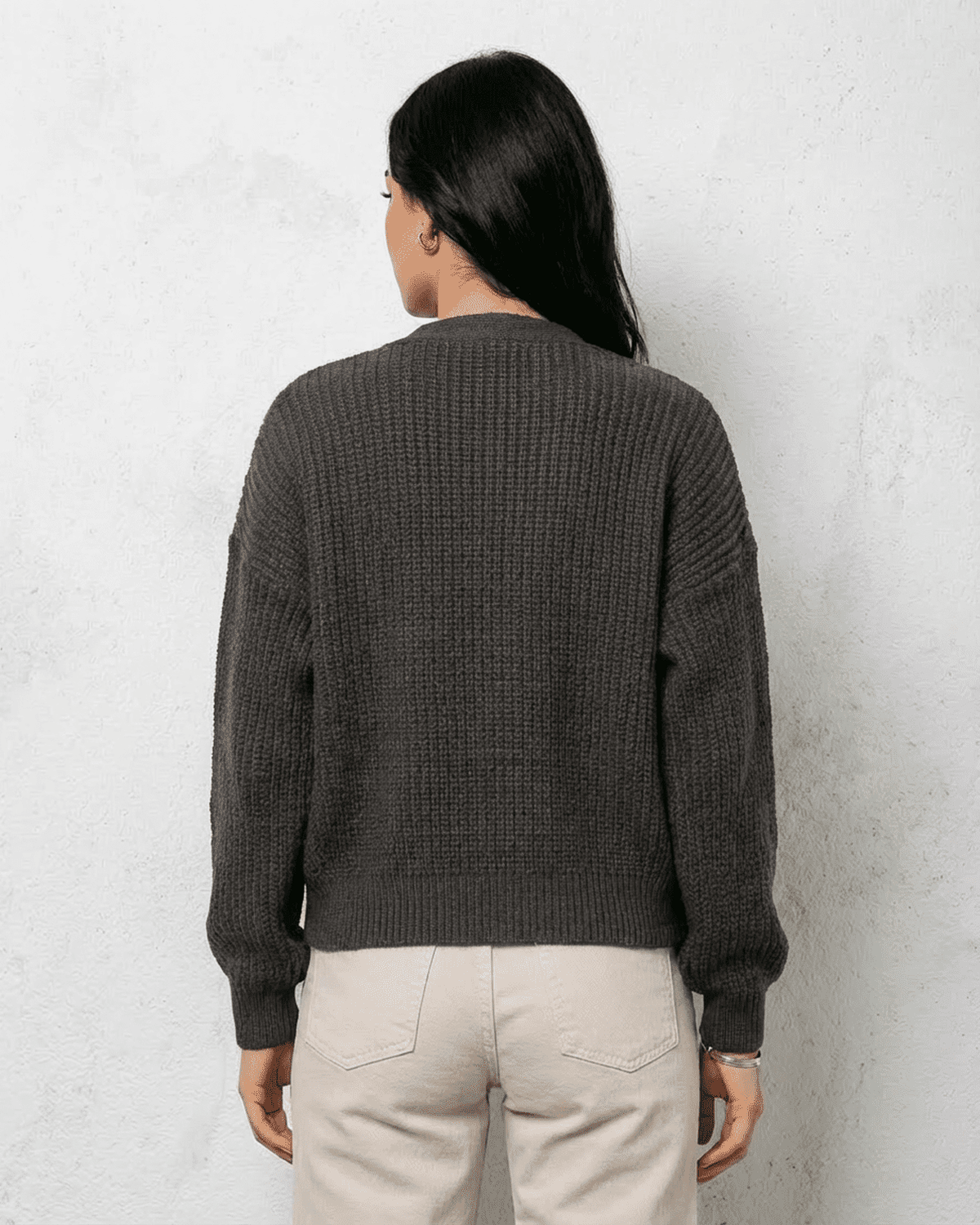 Back view of a woman wearing a Graphite Cardigan by Lauven in charcoal knitwear.