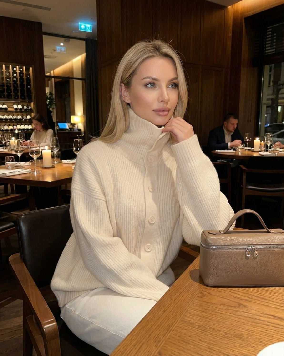 Model wearing the Selene Sweater by Lauven, a ribbed turtleneck button-up women’s sweater, in a cozy restaurant setting.