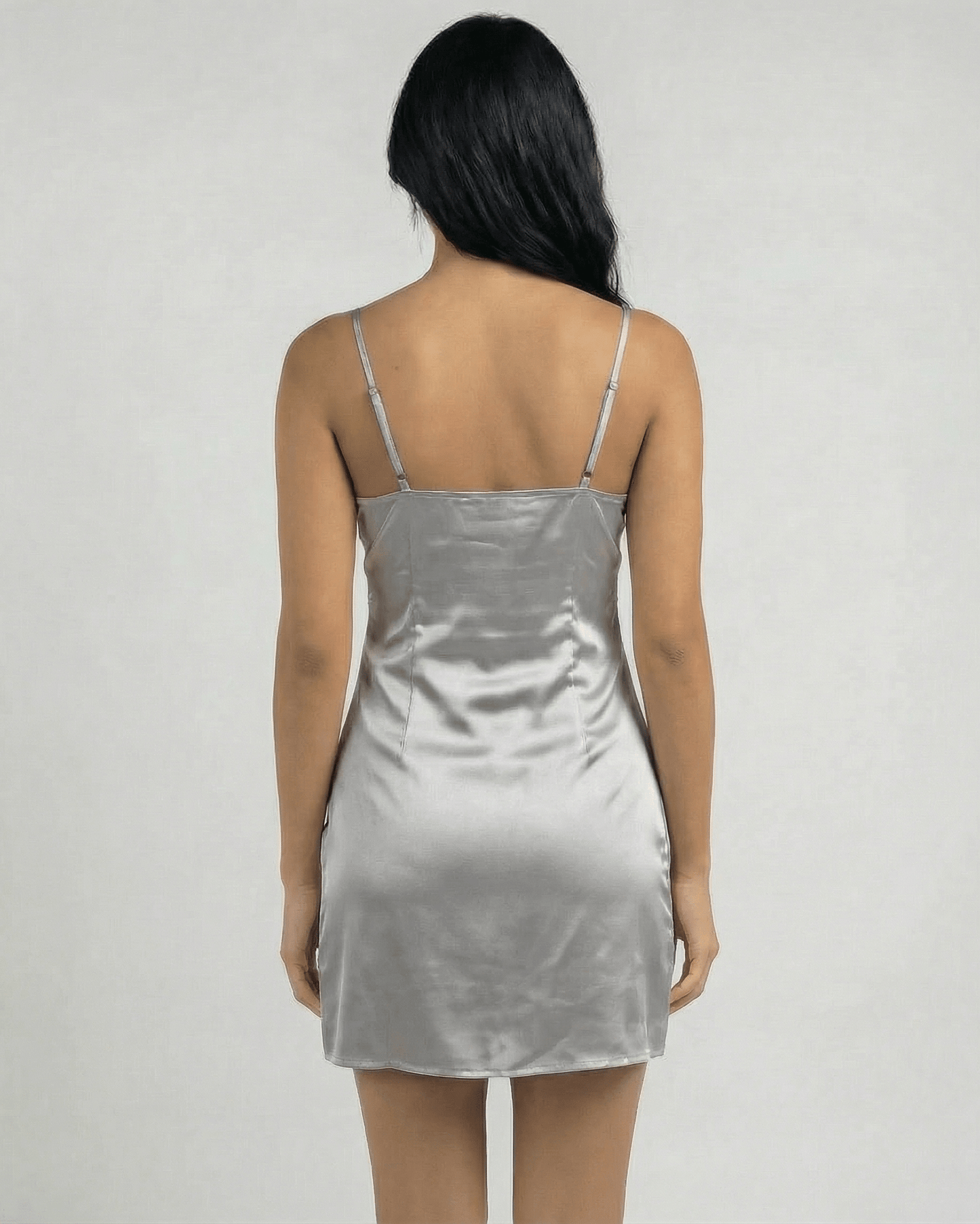 Back view of a woman wearing the Sterling Mini Dress by Lauven, showcasing its sleek satin finish and spaghetti straps.