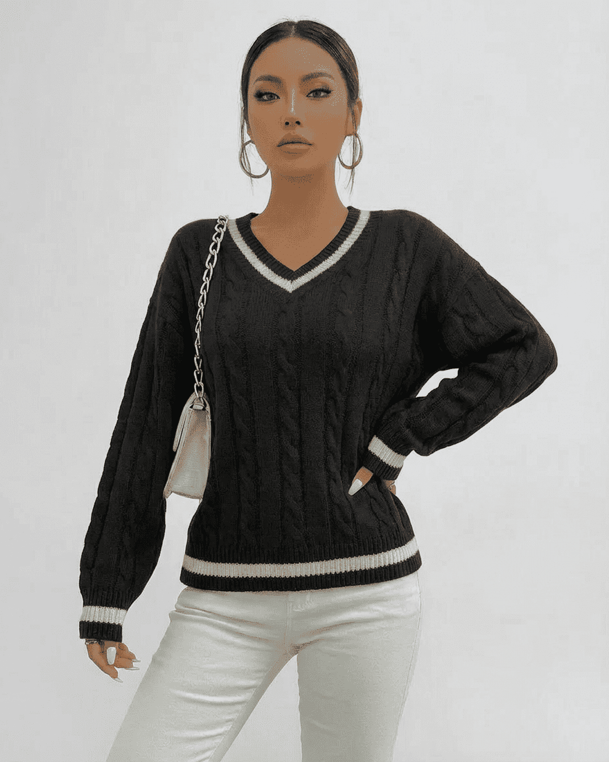 Verona Sweater by Lauven in black cable knit with V-neck and contrasting trim worn with white jeans.
