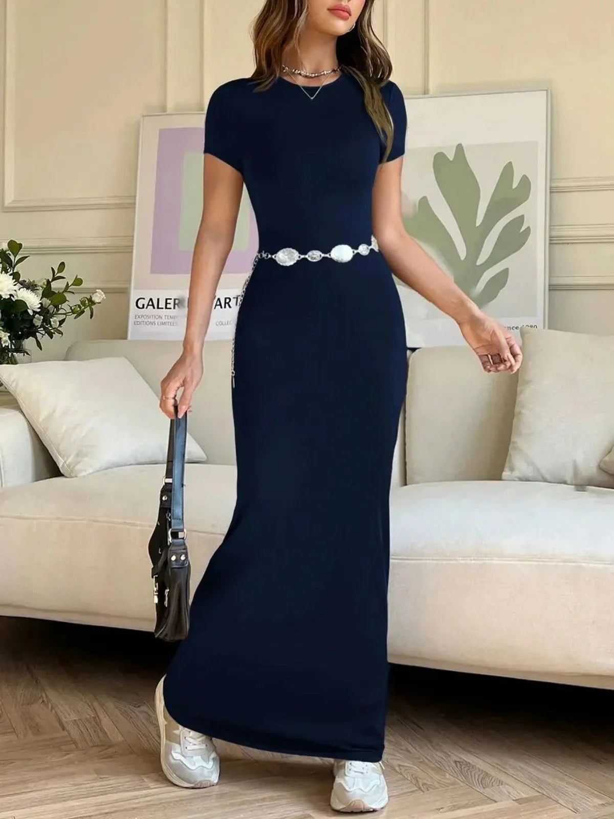 Model wearing the Luna Curve Maxi Dress in navy, featuring a sleek silhouette and stylish belt, suitable for modern elegance.