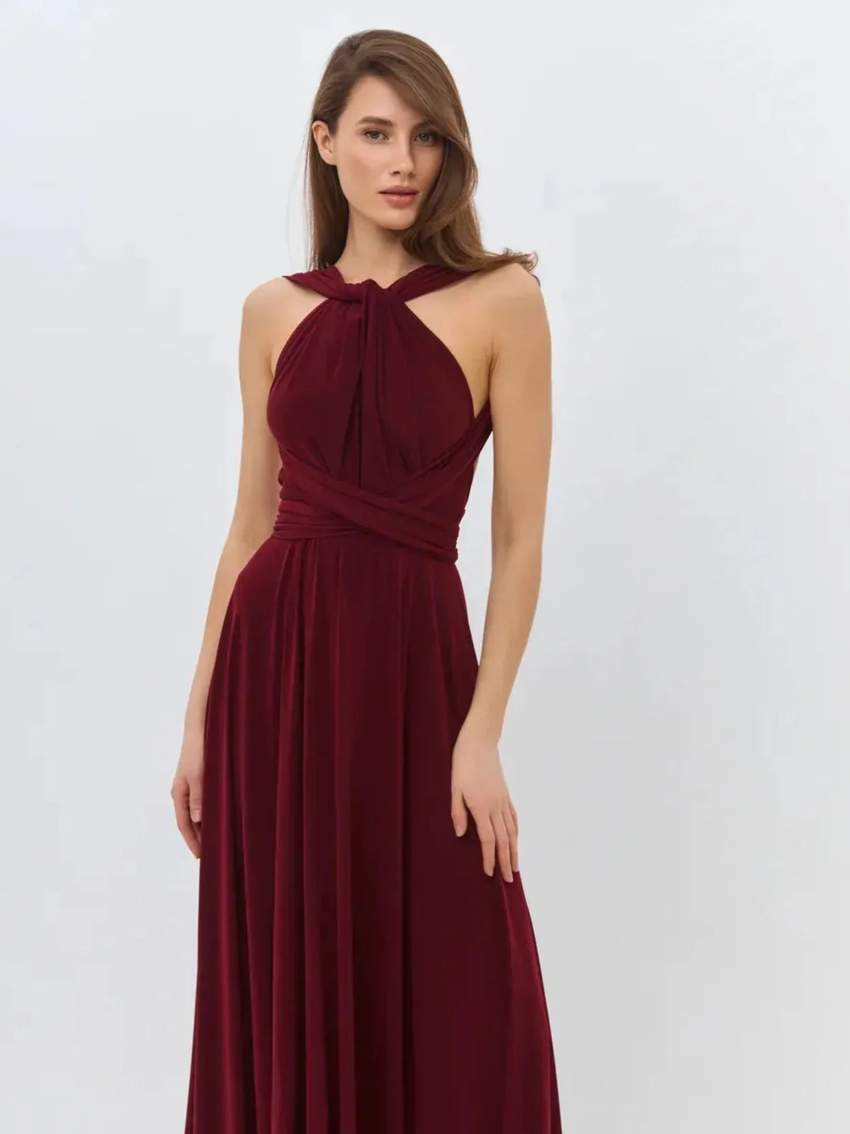Elegant woman wearing a deep burgundy maxi dress with a convertible silhouette and backless design.
