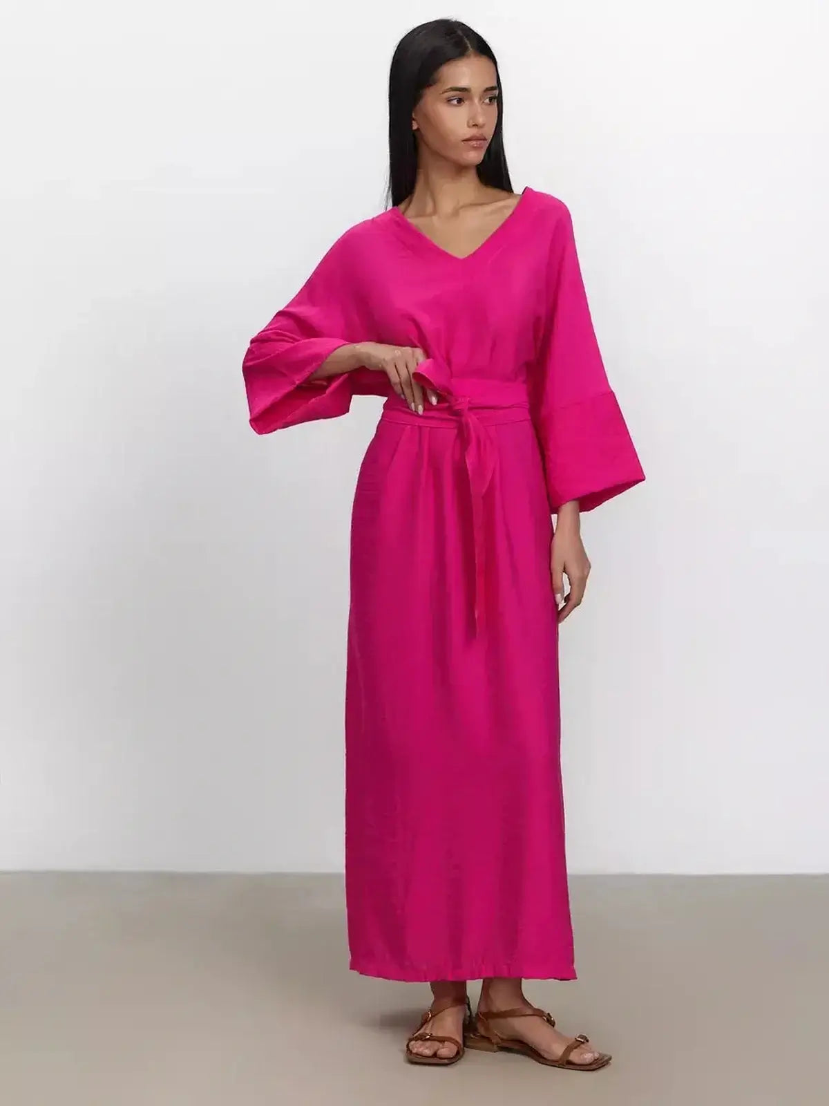 Model wearing a fuchsia maxi dress with a deep V-neckline and kimono sleeves, showcasing effortless elegance.