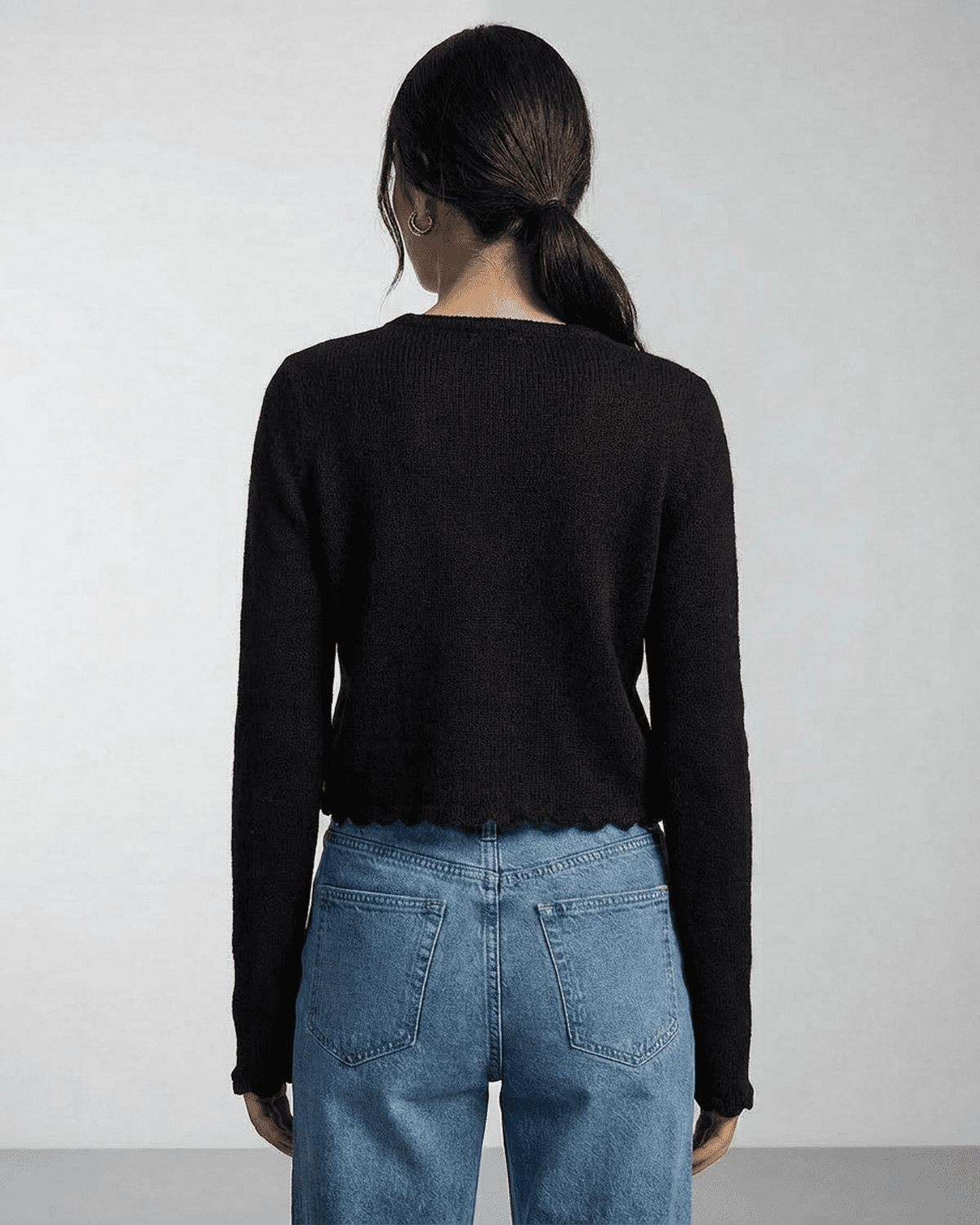 Back view of a woman wearing the Noir Cardigan by Lauven with a cropped fit and elegant design.