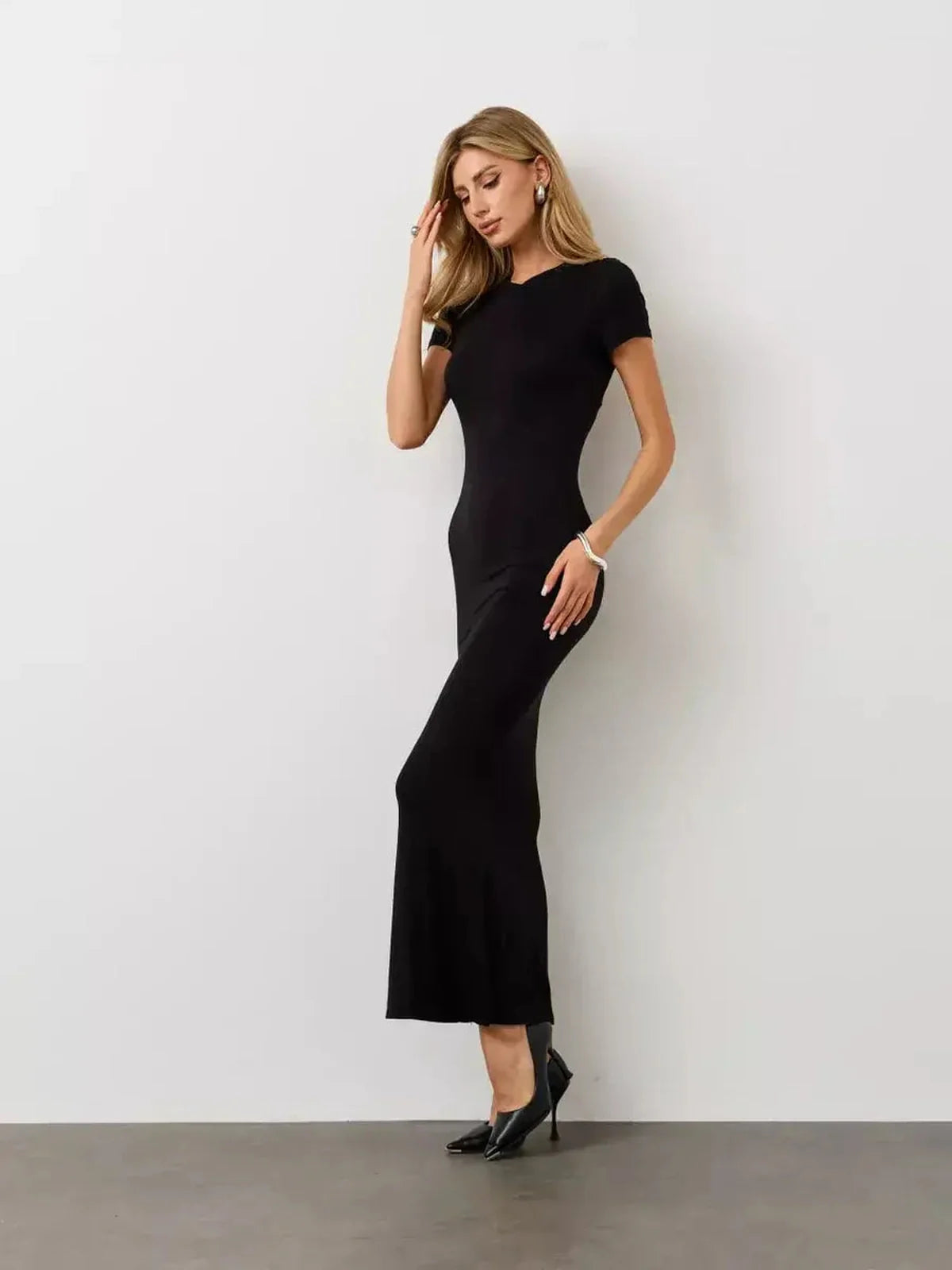 Model showcasing the Noir Curve Maxi Dress, a fluid black gown with a sculpted silhouette and flared hem.