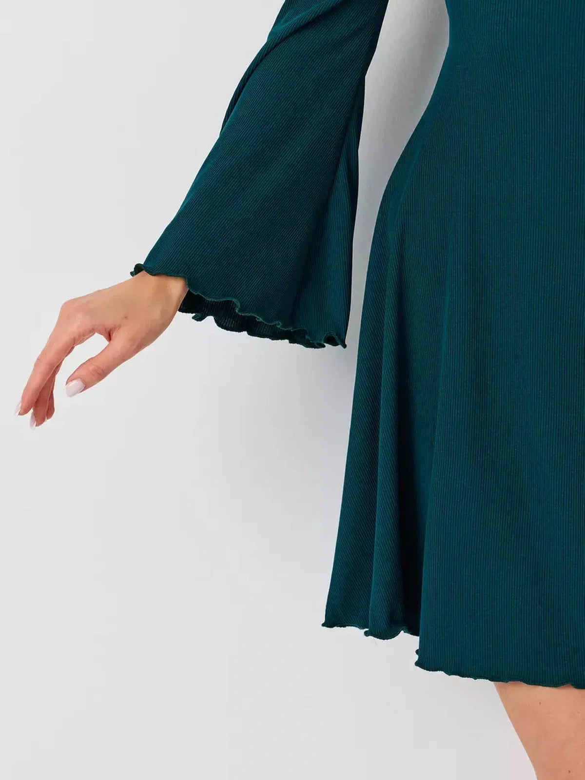 Close-up of graceful bell sleeves and flared hem of the Emerald Whisper mini dress in rich emerald green.