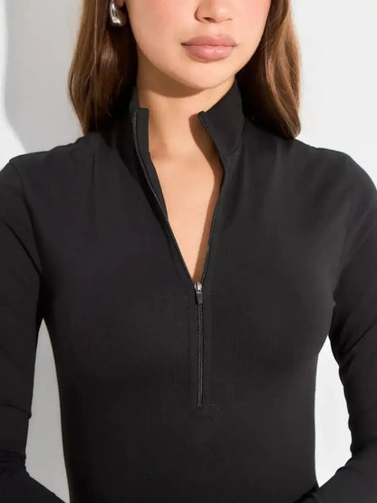 Close-up of a woman wearing a black long sleeve dress with a stand collar and front zip detail.