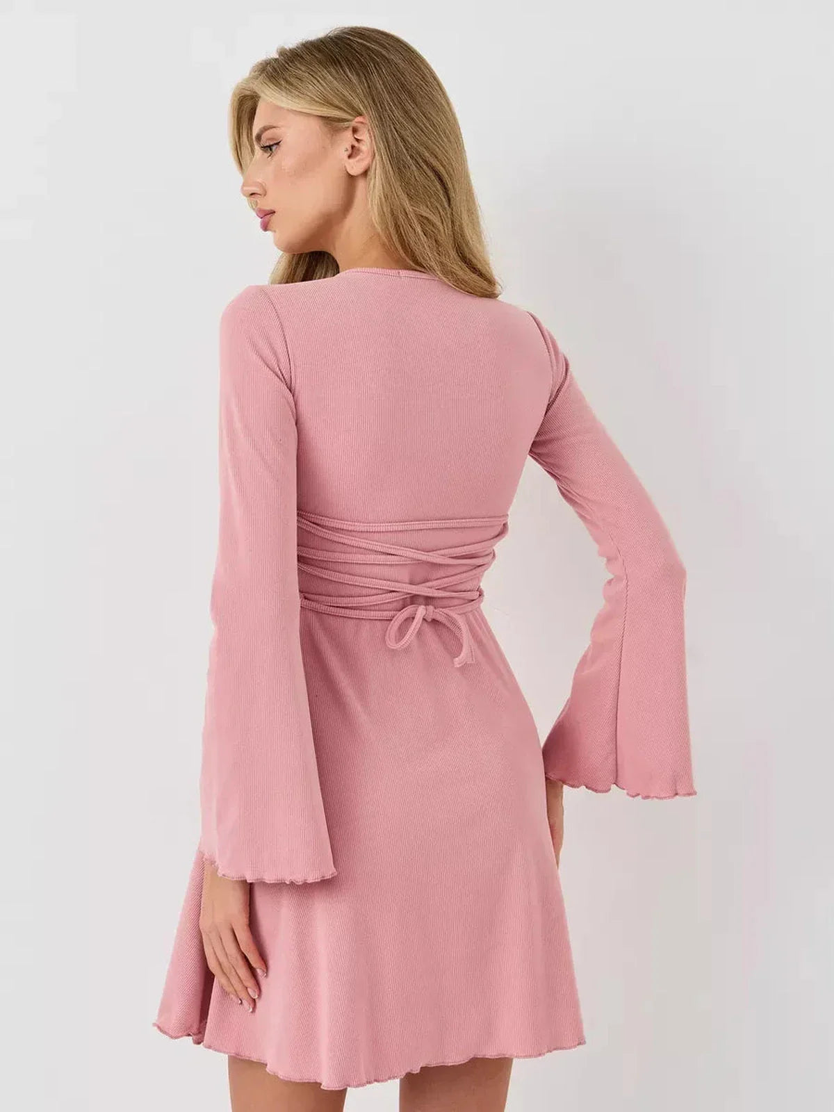 Back view of a woman in a pink Blush Aura mini dress with flared sleeves and a tied waist, showcasing summer elegance.