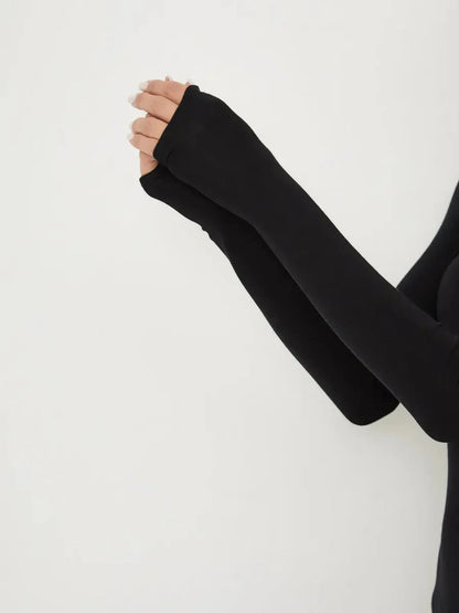 Close-up of hands in black long sleeve top with fingerless design, showcasing elegant minimalist style.