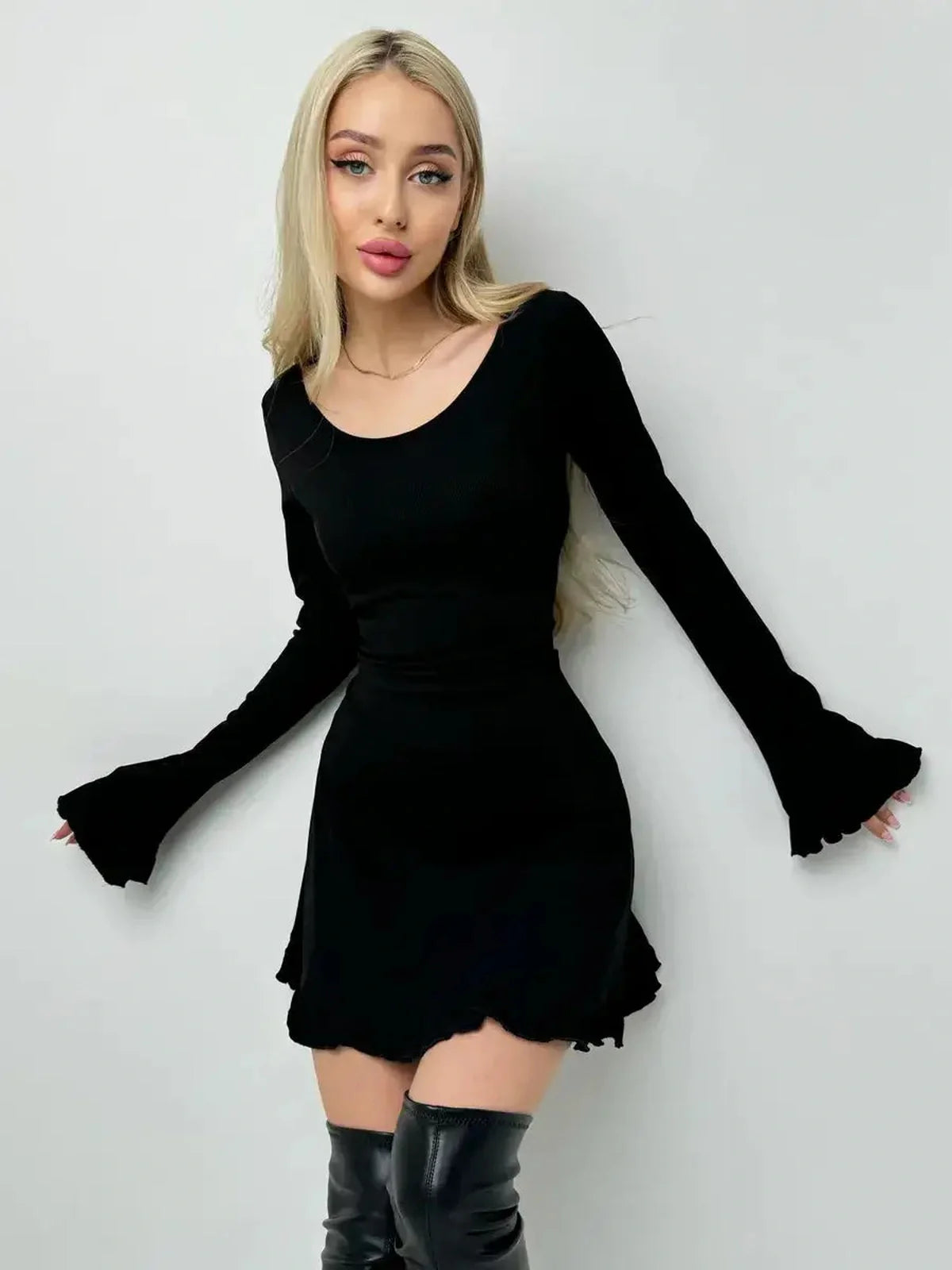 Elegant model in a black Velvet Lace Mini dress with long sleeves and a flared hemline, styled for day-to-night wear.