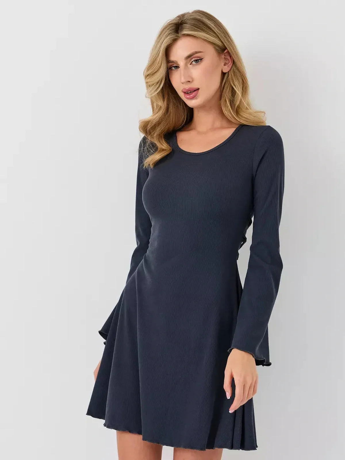 Woman wearing Graphite Grace ribbed mini dress with a sculpted waist and lace-up back tie.