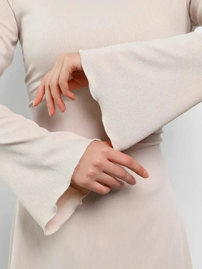 Close-up of soft, ribbed long sleeve dress with flared cuffs in cream, showcasing its elegant texture and fit.