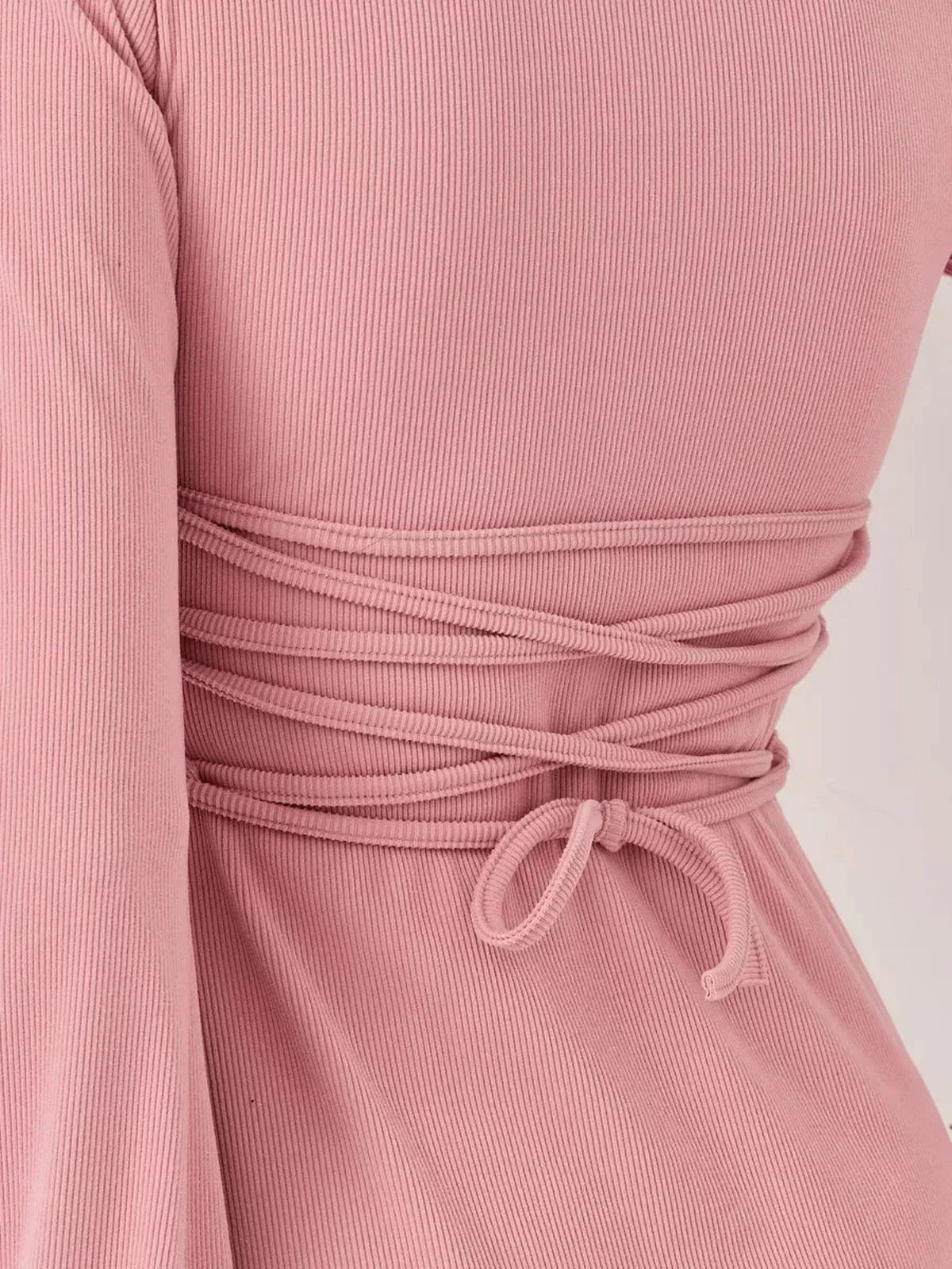 Detail of the Blush Aura mini dress showcasing a tied waist and textured pink fabric.