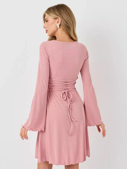 Back view of the Blush Whisper summer dress featuring flared sleeves and a tied waist design in soft pink.