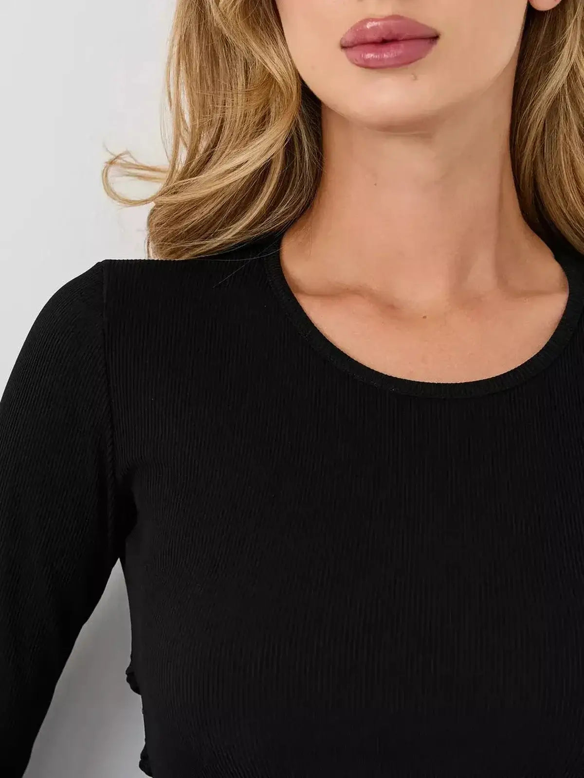 Close-up of a woman's décolletage in a black ribbed long sleeve dress featuring a structured U-neckline.