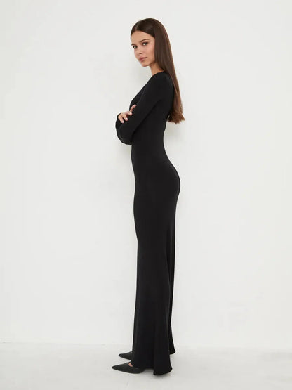 Profile view of a model in the Sculpted Noir full-length black dress, showcasing its sleek, minimal design and flattering fit.