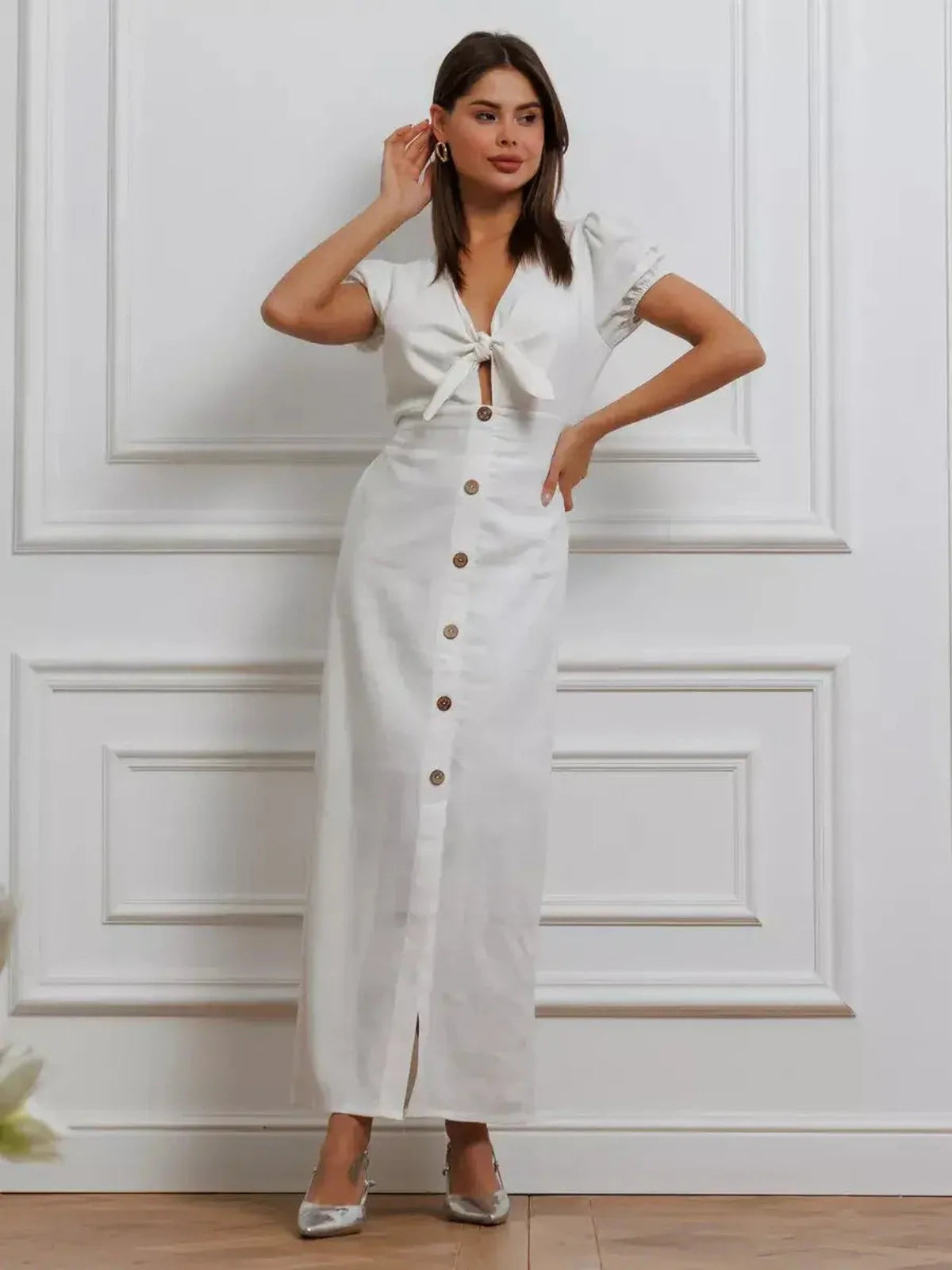 Woman in white Maxi Dress Pearl Whisper with tie-front and puff sleeves, showcasing a chic, minimalist style.