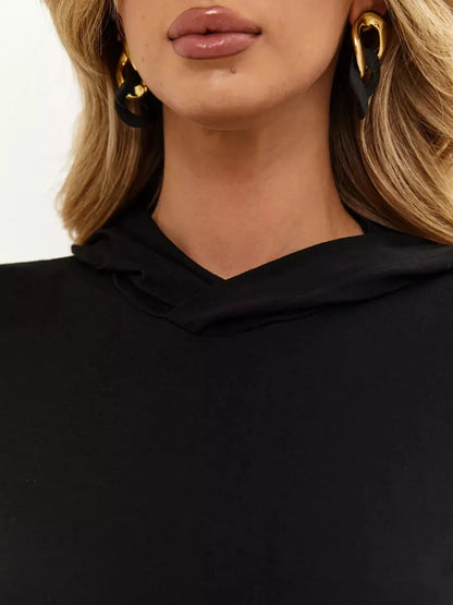 Close-up of a woman wearing the Noir Maxi Dress, showcasing its hood detail and elegant earrings.