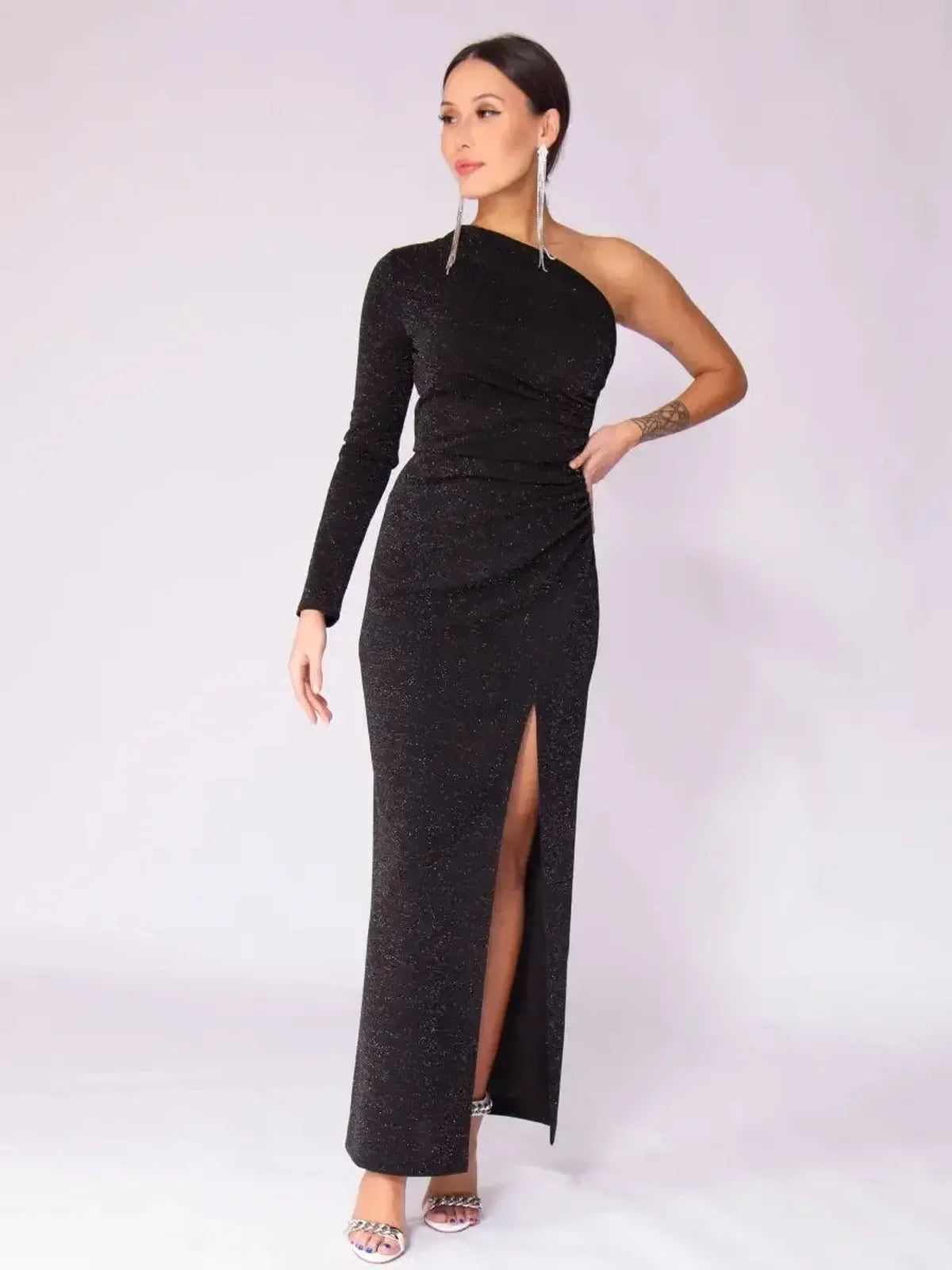 Model wearing Luna Noir Maxi Dress featuring a one-shoulder design, drape, leg slit, and elegant sparkle for evening wear.