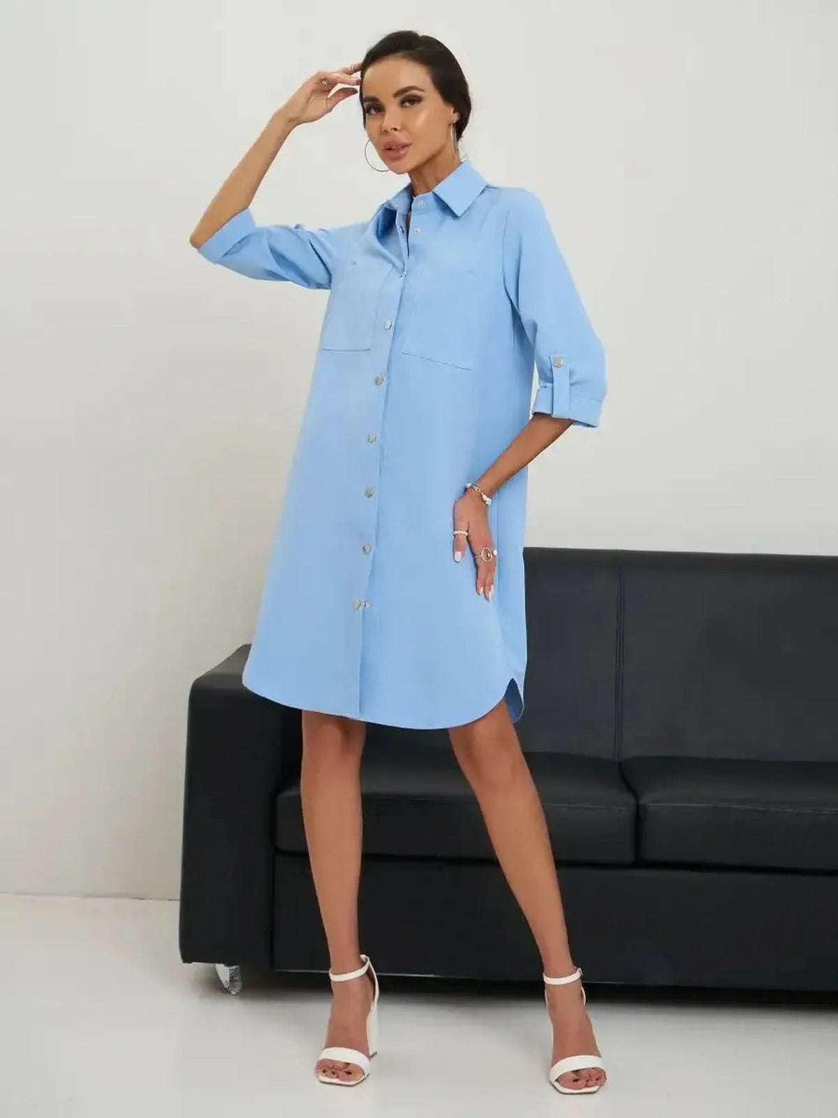 Woman in a chic sky-blue Skyline Mini Dress, showcasing a stylish button-up design and rolled sleeves, perfect for summer.