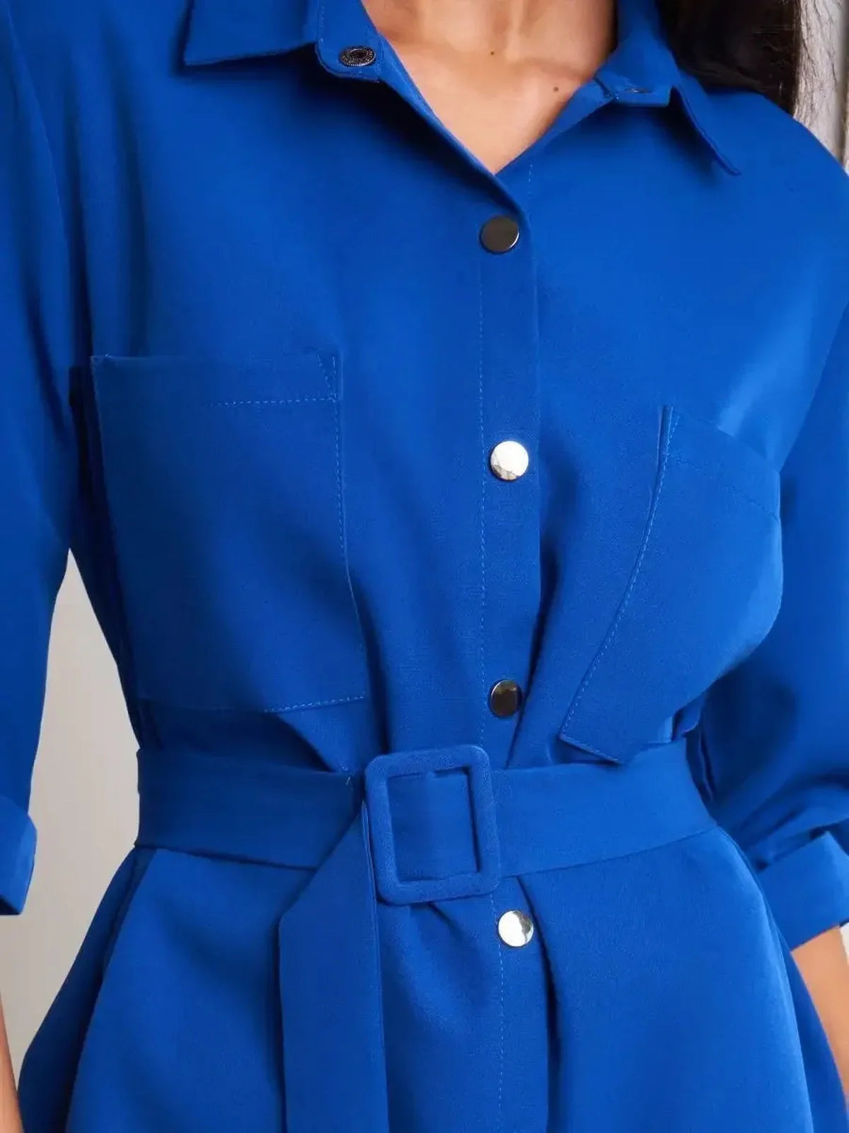 Close-up of the Cobalt Charm Mini Dress featuring a vibrant blue color, snap-buttons, and a stylish, adjustable waist belt.