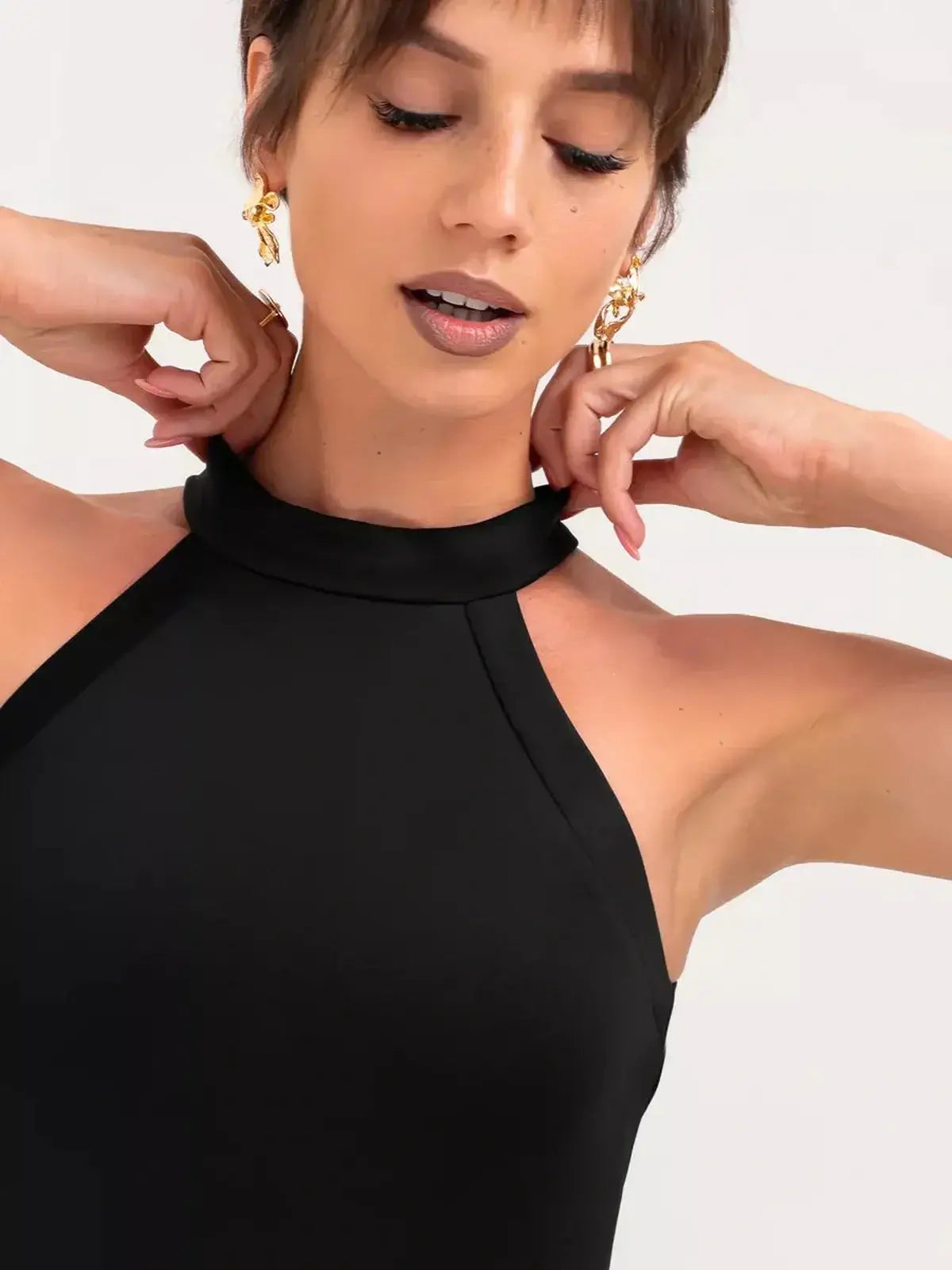 Close-up of a woman in a black halter neck dress showcasing the sleek design of Midnight Sculpt.