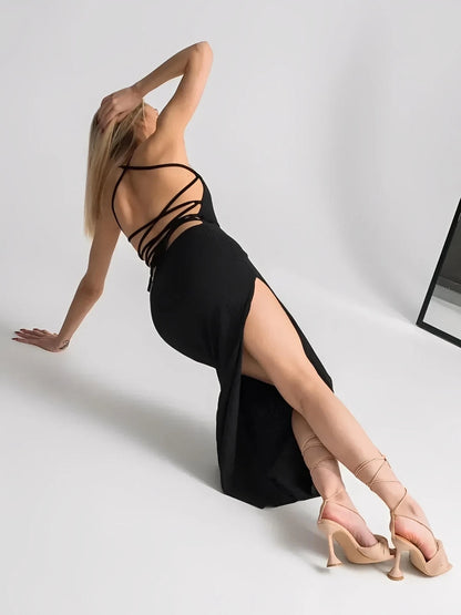 Woman showcasing the Noir Lace Midi Dress, featuring an open lace-up back and thigh-high slit, exuding elegance and sophistication.