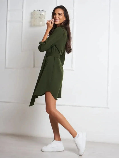 Model wearing an olive green belted shirt mini dress with white sneakers, showcasing a relaxed, minimalist style.