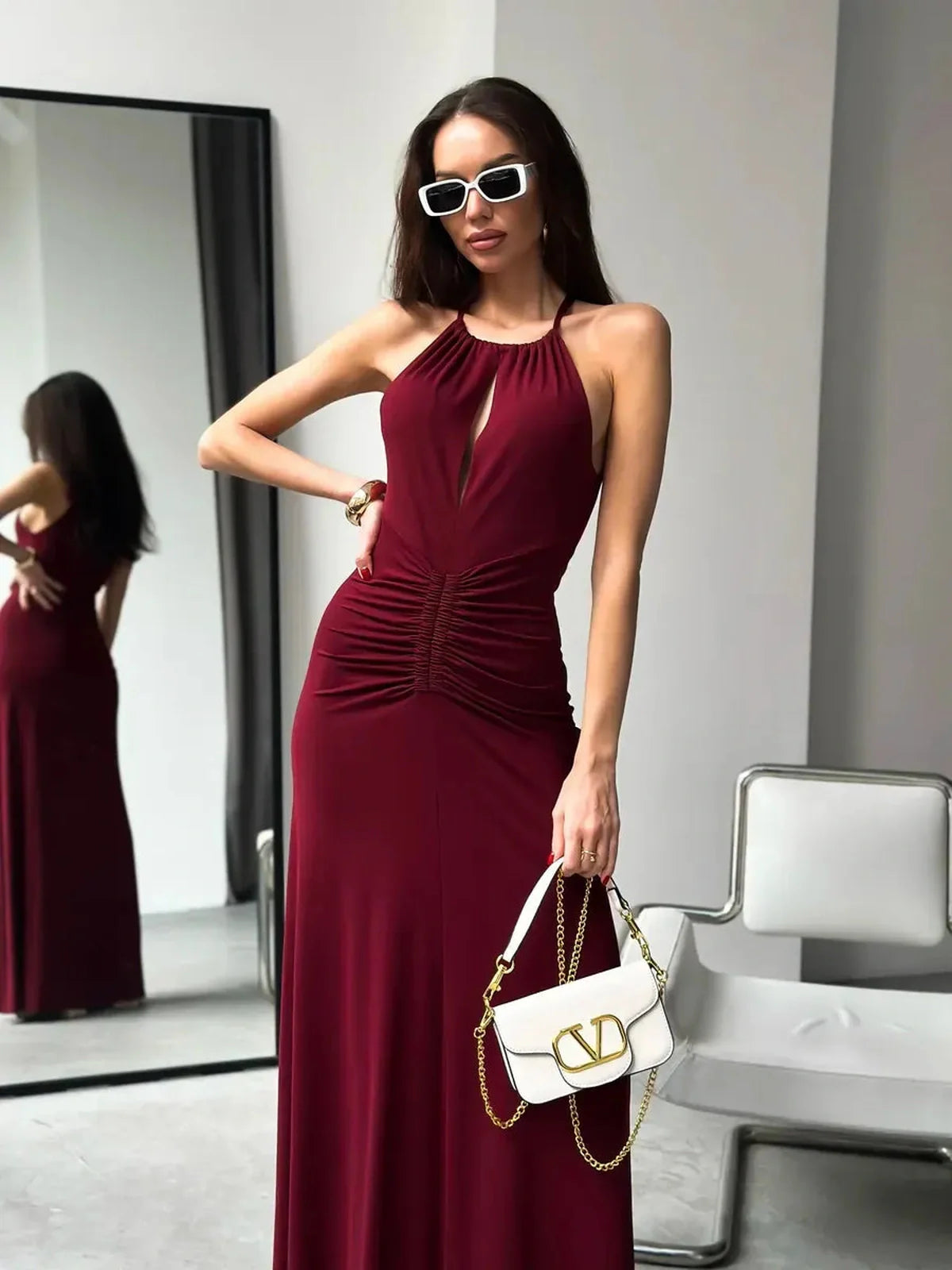 Maxi Dress Élan featuring a draped halter design and ruching, portrayed in a chic setting with accessories.