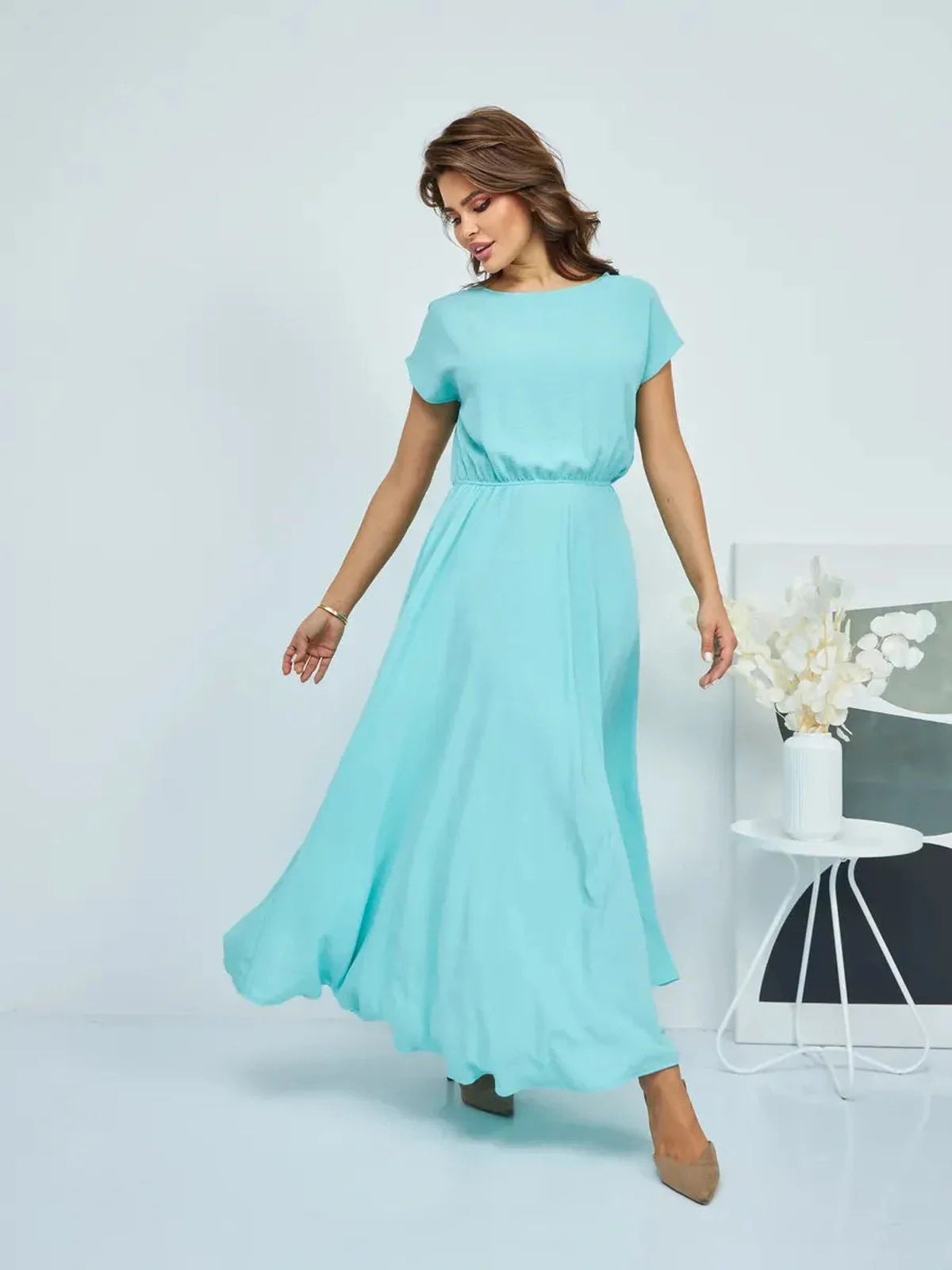 Elegant woman in a flowing aqua maxi dress, showcasing a sophisticated silhouette, perfect for evening events.