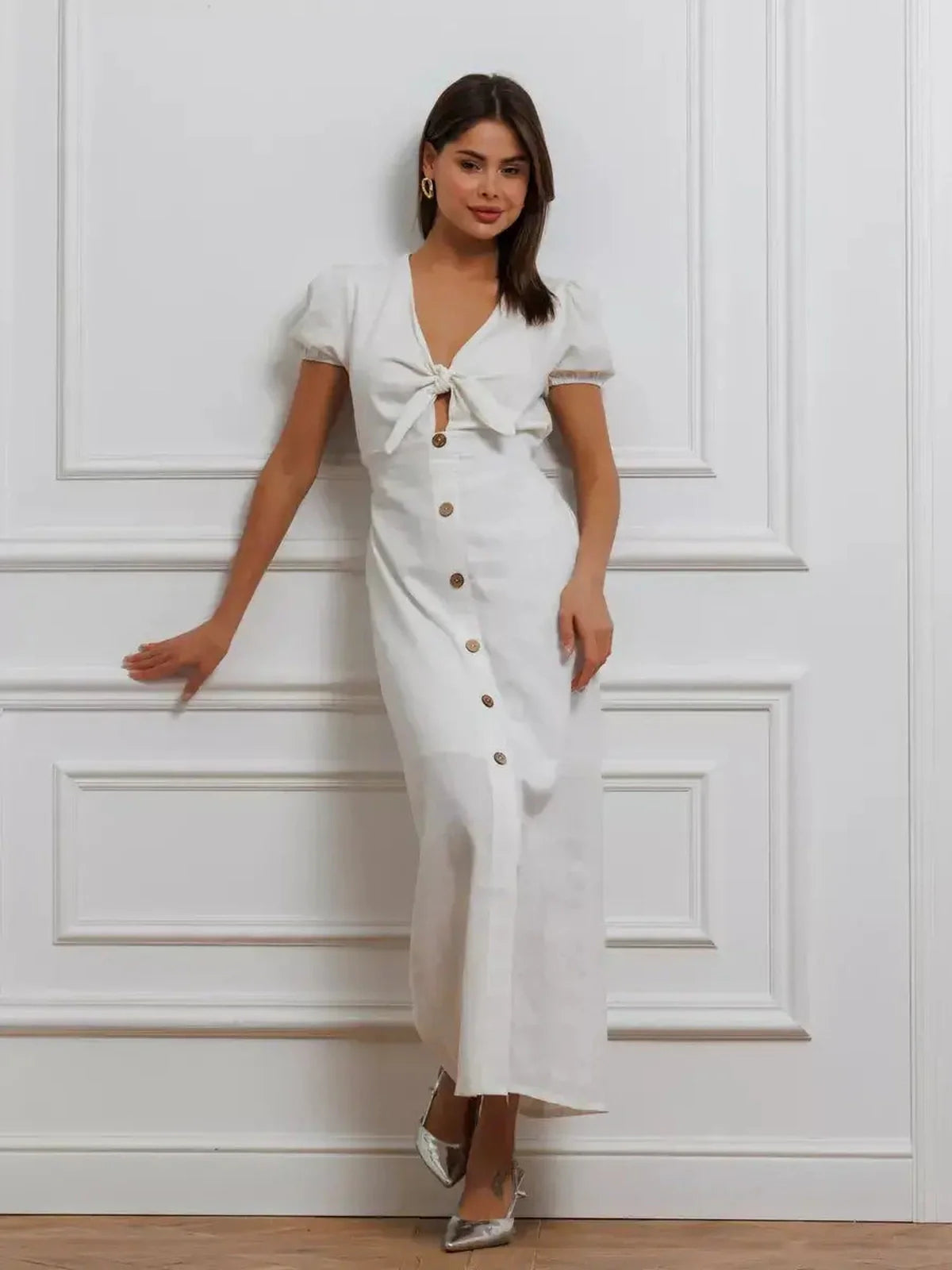 White maxi dress with tie-front, puff sleeves, and button-down skirt, exuding minimalist elegance and sophistication.