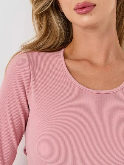 Close-up of a woman wearing a scoop-neck ribbed pink dress with soft pink hues, highlighting elegance and style.