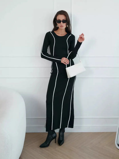 Model in a black Midnight Curve Maxi Dress featuring elegant white contrast piping, exuding sophistication and style.