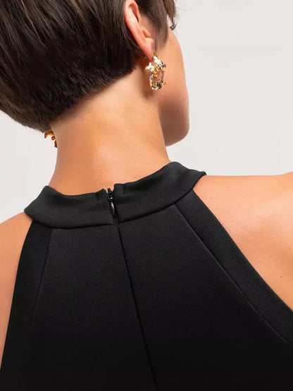 Close-up of the back of a stylish black midi dress with halter neckline and concealed zipper, showcasing refined elegance.