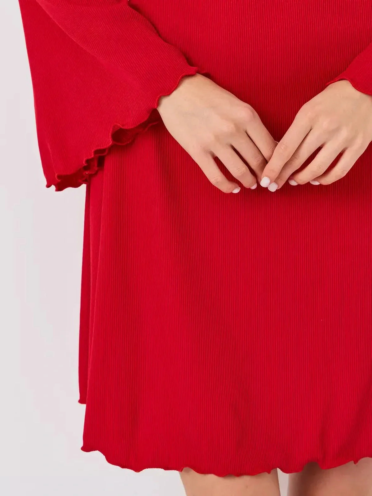 Close-up of hands on a red flare cutout mini dress showcasing its textured fabric and playful ruffled hem.