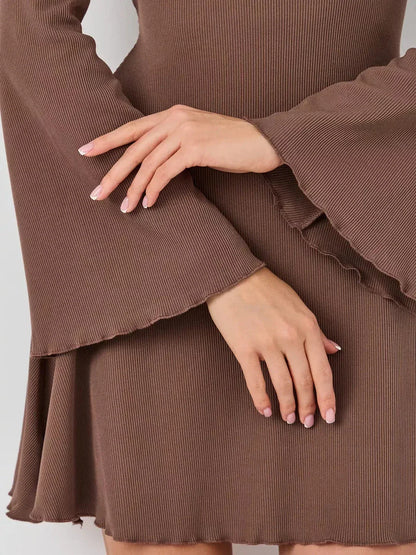 Close-up of hands in a brown ribbed mini dress featuring bell sleeves and a flared hem, showcasing elegance and style.