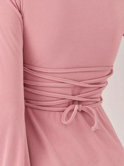 Close-up of the Blush Flare mini dress showcasing its soft pink ribbed fabric and unique tie-back detail.