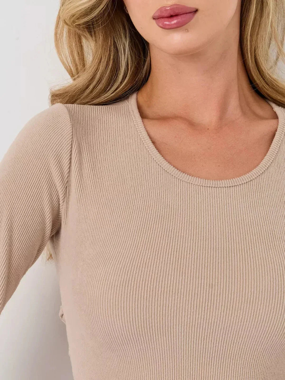 Close-up of a warm beige ribbed mini dress featuring a U-neckline and long sleeves, showcasing its luxe fabric.