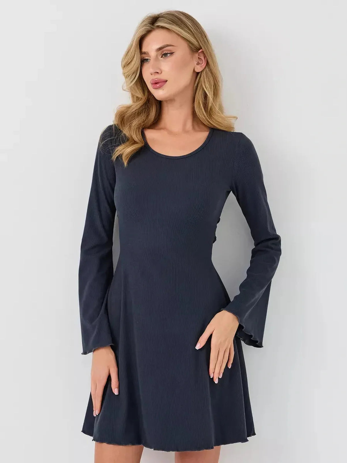 Model showcasing the stylish Graphite Grace mini dress with long sleeves and flared cuffs for a chic look.